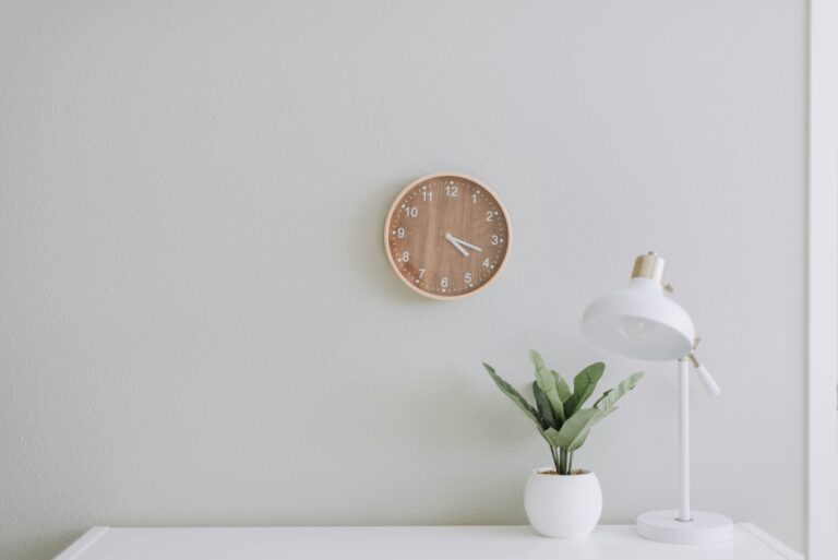 white desk with green plant sitting on it in front of minimal wall