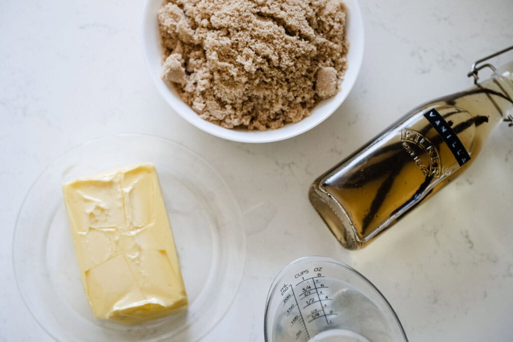 Butter, brown sugar, vanilla, and water on a white surface