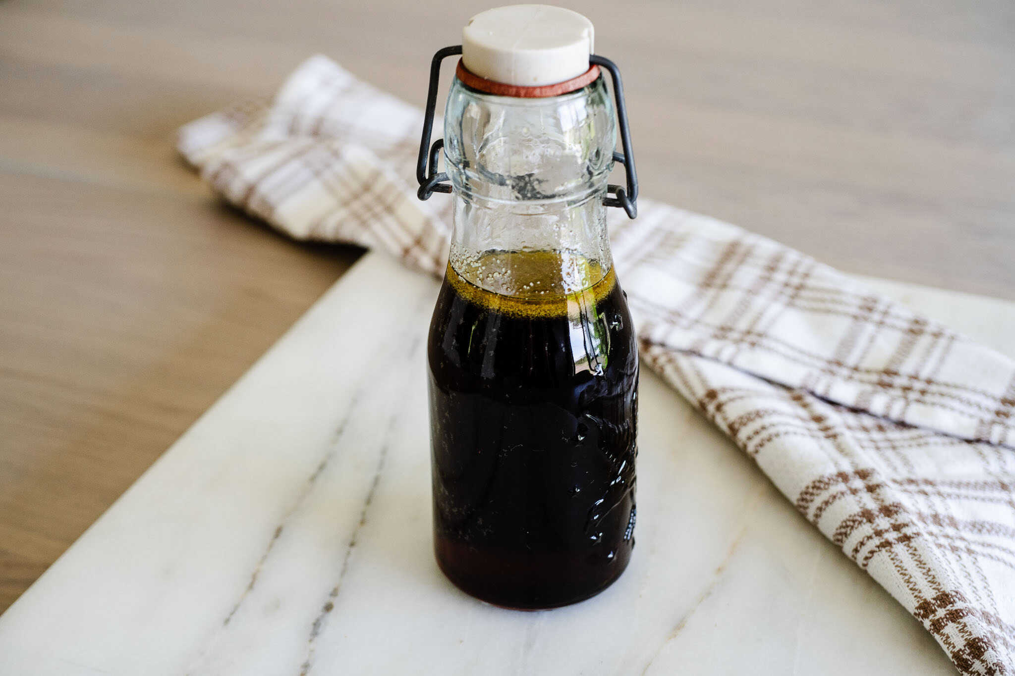 glass bottle of brown butter syrup stands on a white counter