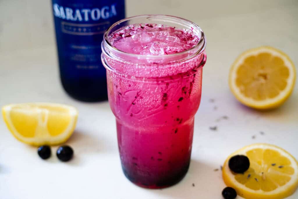 A cup layered with lemonade, lavender syrup, and blueberry sauce, then topped with sparkling water