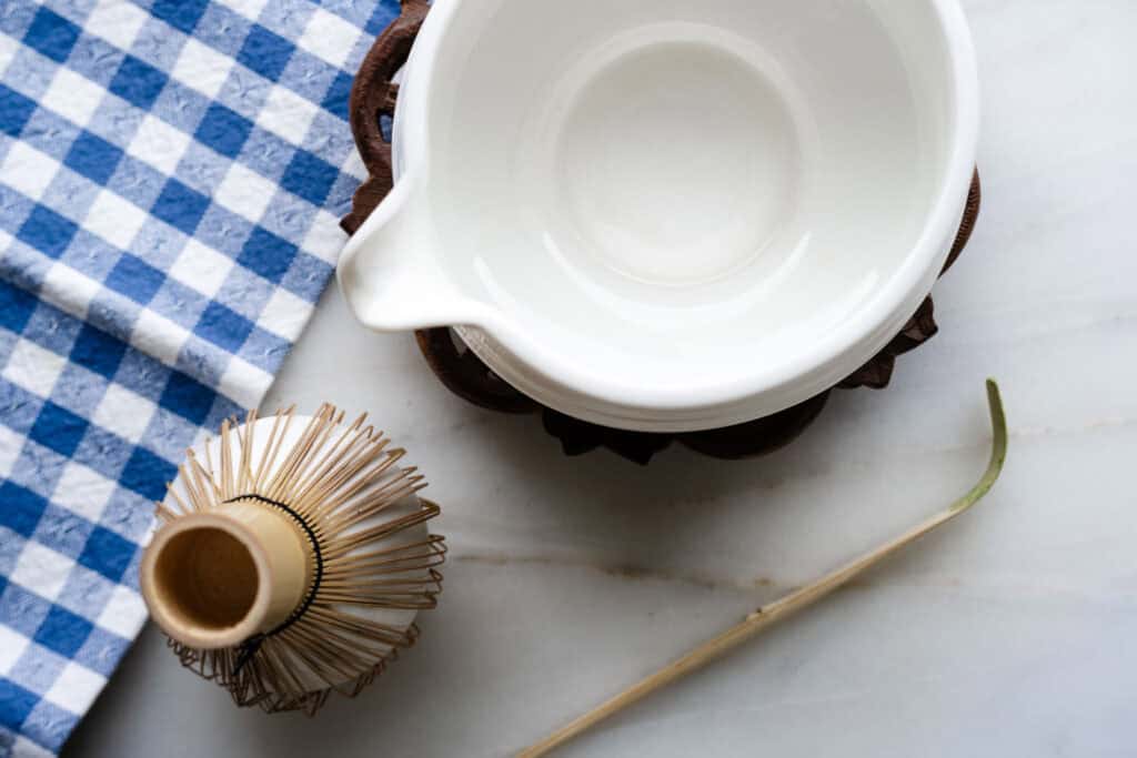 bamboo whisk white bowl and scoop with a blue napkin