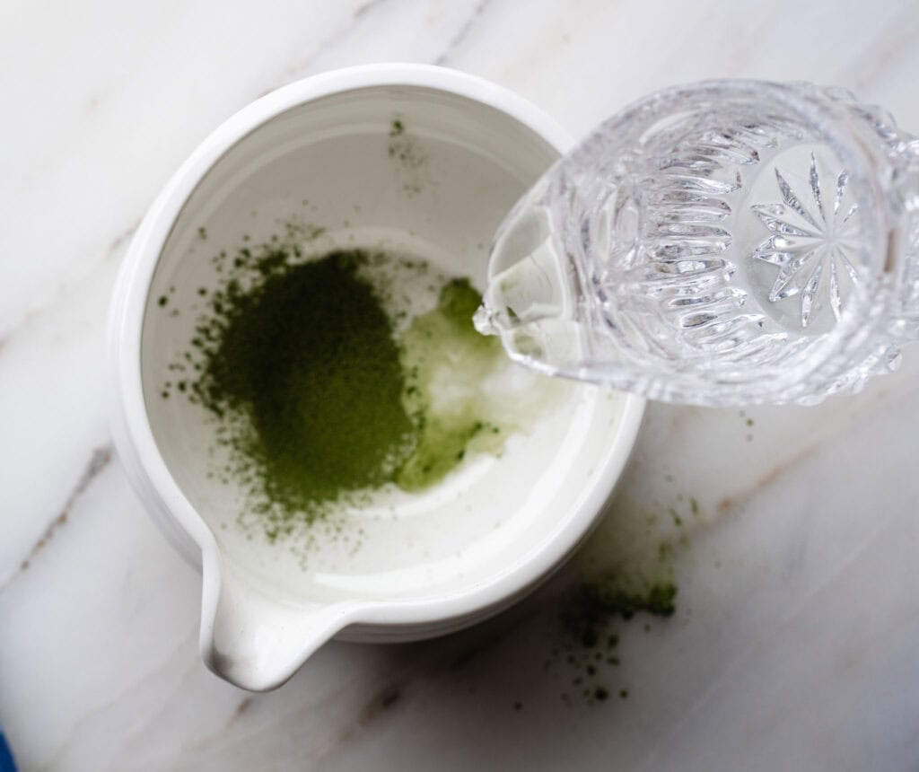 water streaming into a white bowl with sifted matcha