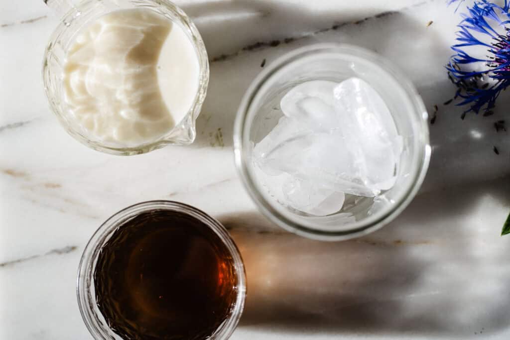 glass filled with ice, matcha and milk ready to pour in