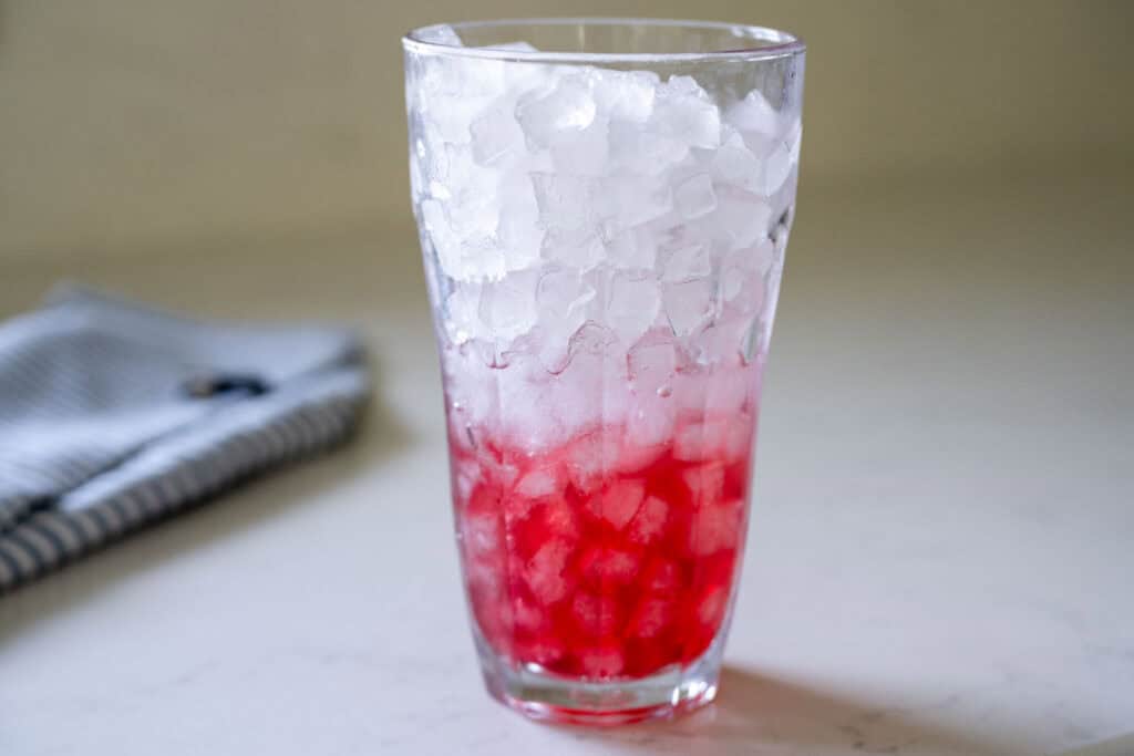 raspberry syrup added to the bottom of an ice filled cup