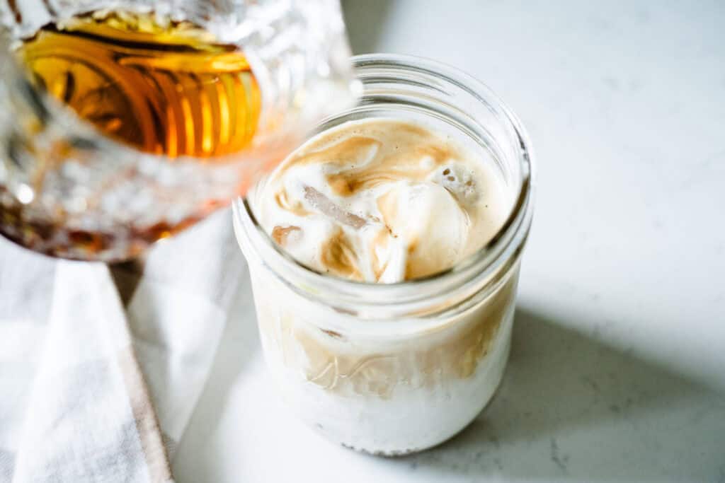 syrup being poured into an iced latte
