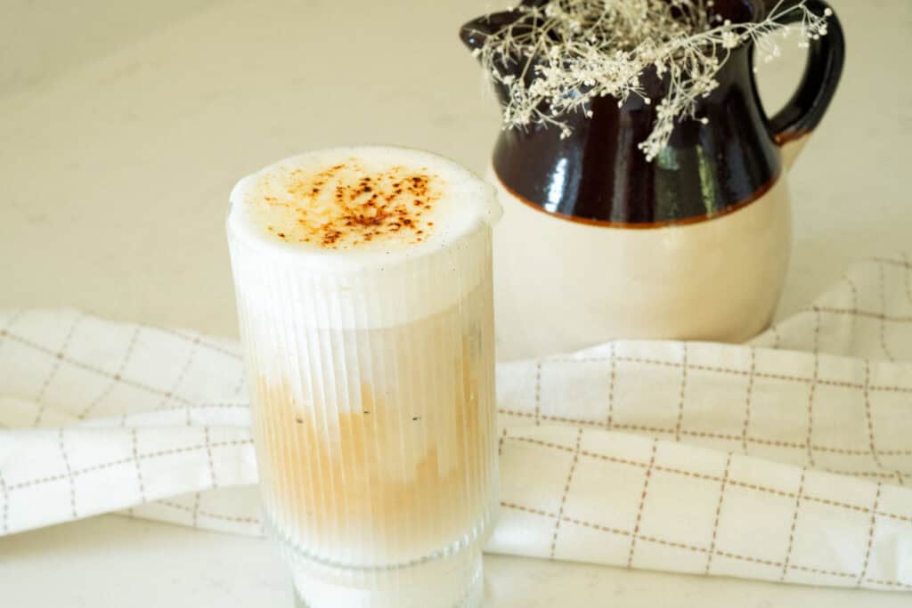 iced latte in front of a jar with dried florals