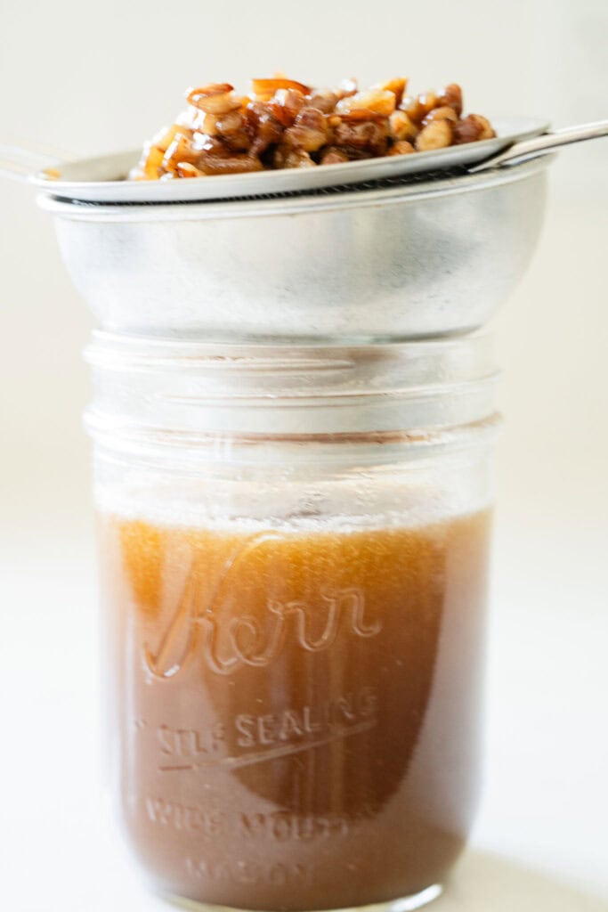 pecan being strained from a rich syrup