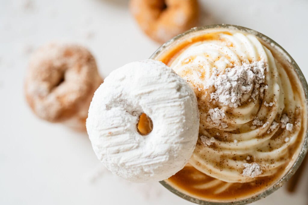 iced latte topped with cold foam and a donut