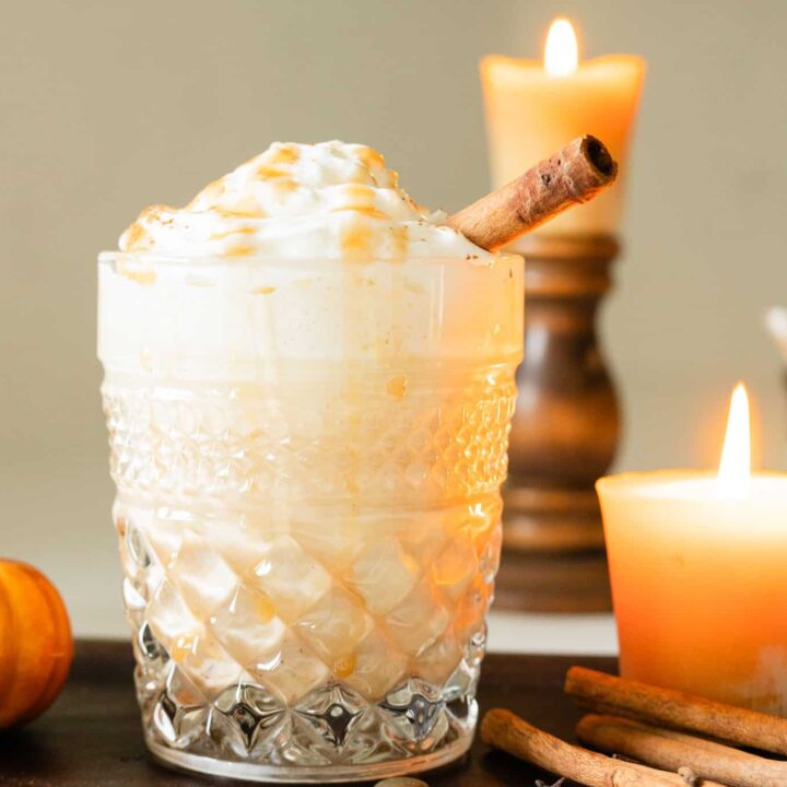 iced pumpkin eggnog topped with whipped cream and a cinnamon stick