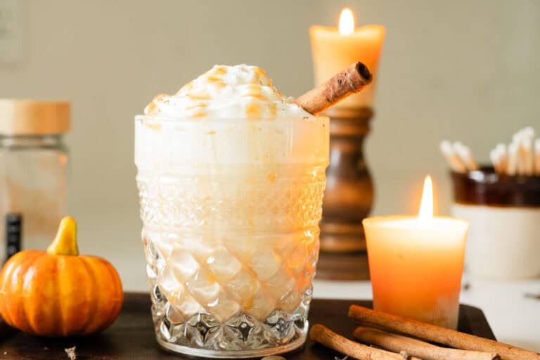 iced pumpkin eggnog topped with whipped cream and a cinnamon stick