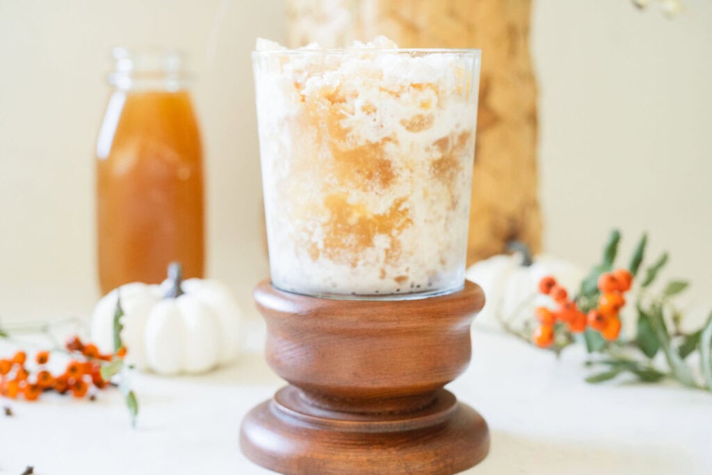 creamy and icy drink surrounded by white pumpkins and orange berries