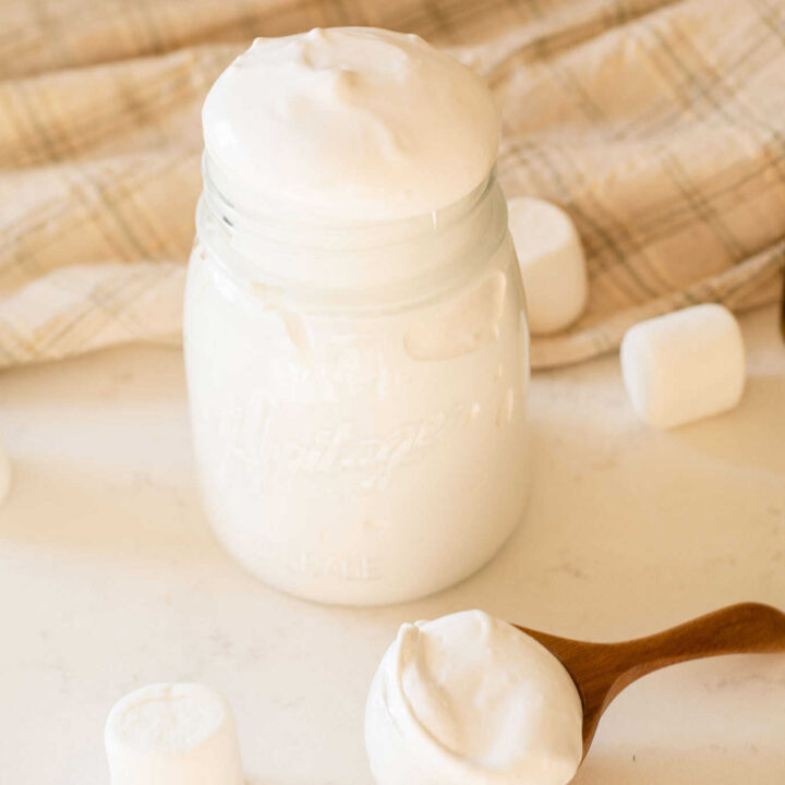 jar with marshmallow fluff surrounded by a scoop and vanilla beans