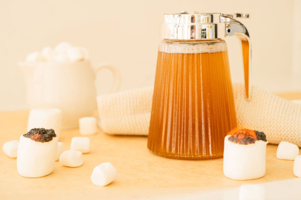 jar with syrup surrounded by flaming marshmallows