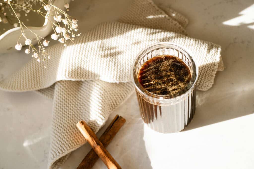 syrup in a jar surrounded by cinnamon sticks
