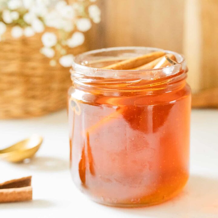 jar of cinnamon honey with flowers in the background