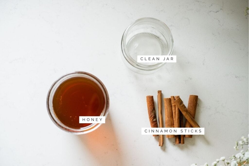 honey, cinnamon sticks, and a clean jar on the counter
