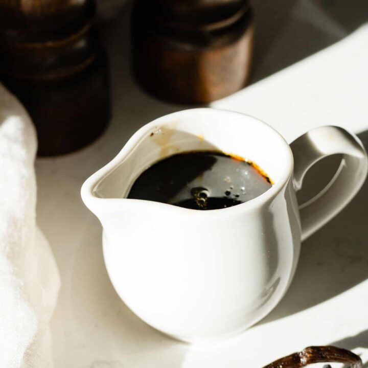 small white pitcher with syrup with a vanilla bean on the side